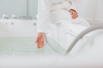 female in bath robe checking the temperature of the water